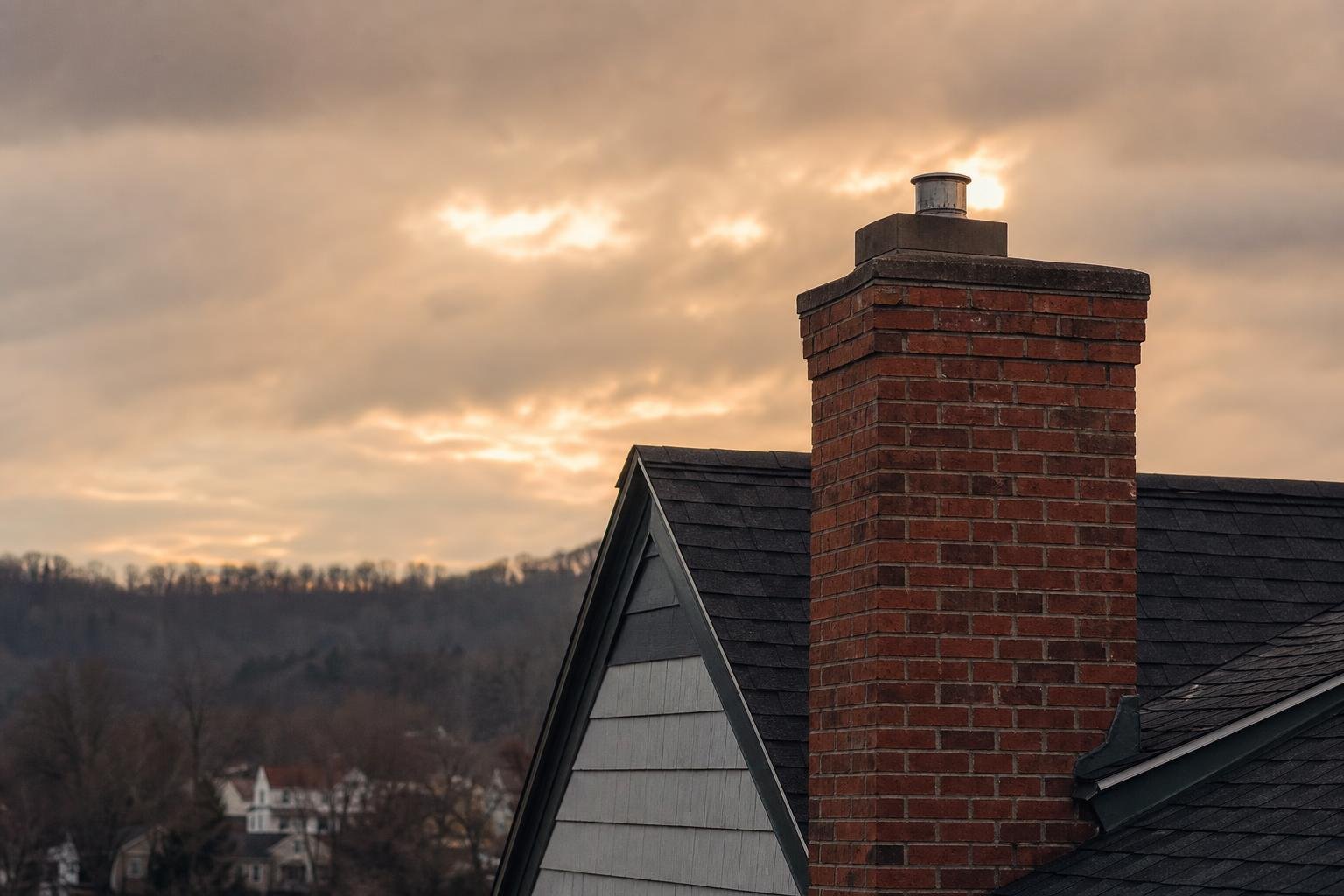 Brick chimney and roofline against a cloudy sky