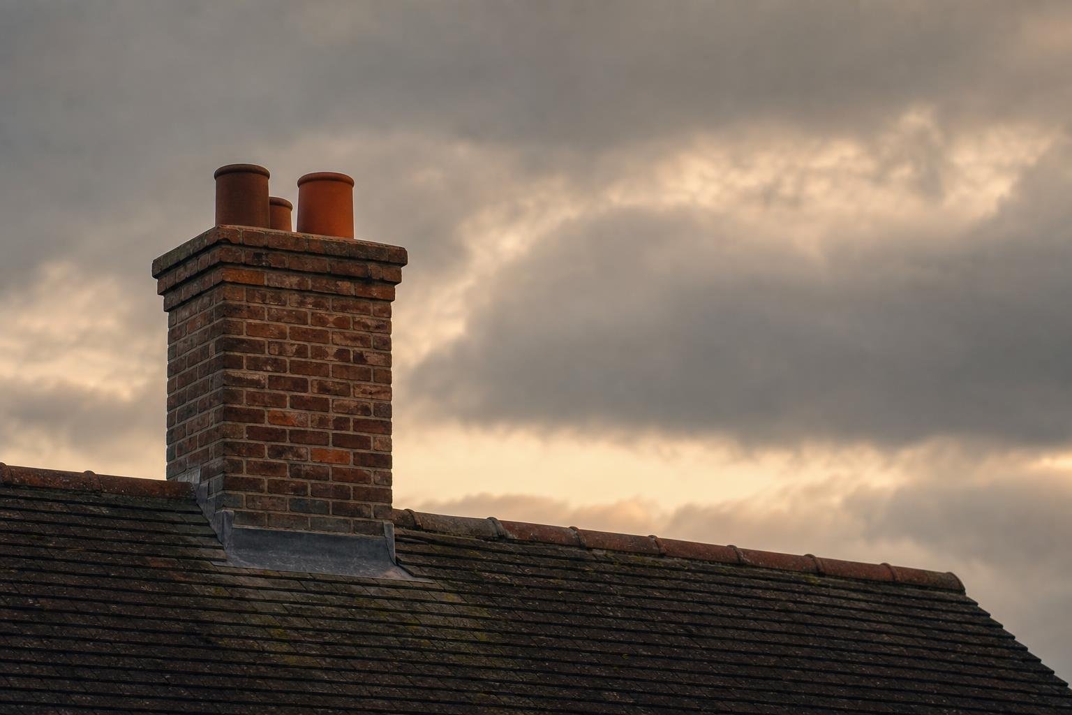 Brick chimney and roofline against a cloudy sky